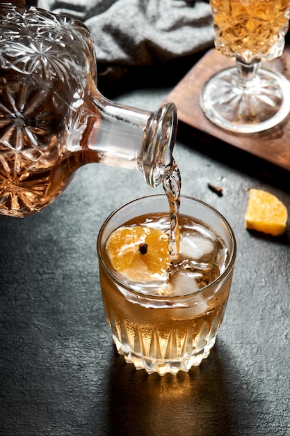 Zdjęcie robienie drinka z pomarańczową whisky i miodem, koktajl z owocami na rustykalnej czarnej bazie