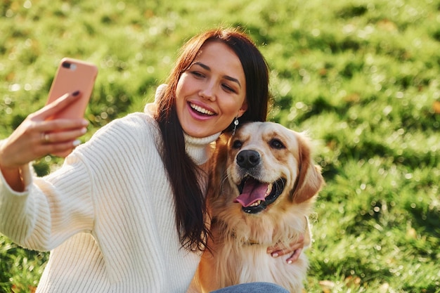 Robienie selfie Młoda kobieta spaceruje z Golden Retriever po parku