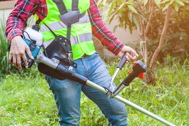 Robociarz trzyma gazonu kosiarza maszynową tnącą trawę w ogródzie na ranku