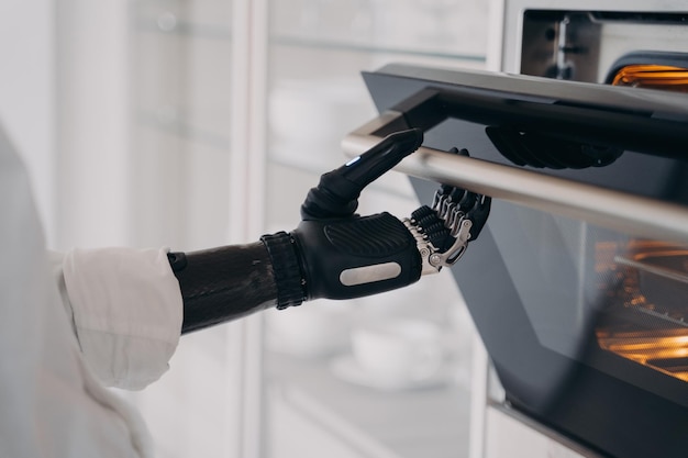 Robotyczna cyber ręka osoby niepełnosprawnej otwiera piekarnik w kuchni Osoba po amputacji gotuje