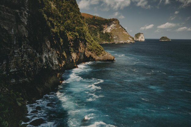 Zdjęcie rock ocean shore timelapse aerial viea z dramatycznymi uderzającymi falami na klifie w indonezji nusa