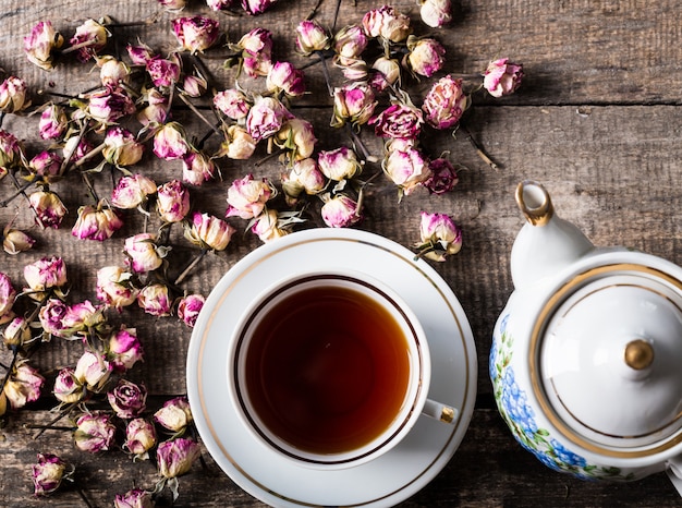 Rocznik filiżanka z kwitnącą herbatą i teapot kwitniemy na drewnianym tle