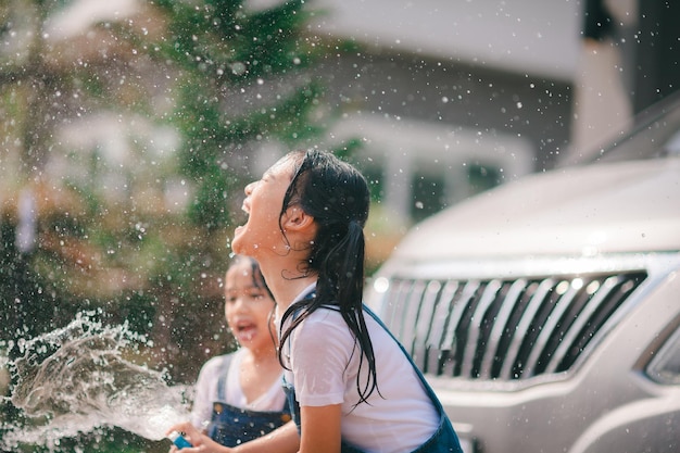 Rodzeństwo Azjatek myje samochody i bawi się w domu w upalny letni dzień