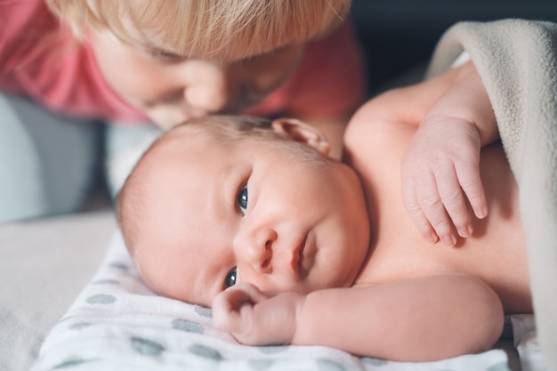 rodzeństwo zaprzyjaźnia się z siostrą całuje swojego młodszego brata dziecko maluch dziewczynka i nowonarodzony chłopczyk