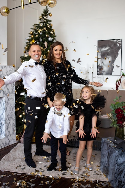 Rodzice i ich szczęśliwe dzieci córka i syn bawią się konfetti na Boże Narodzenie w domu