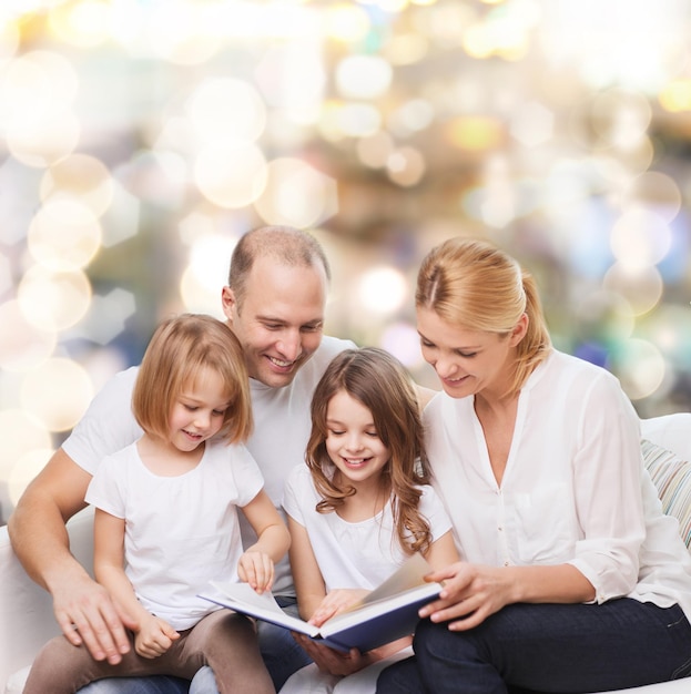rodzina, dzieciństwo, wakacje i ludzie - uśmiechnięta mama, ojciec i małe dziewczynki czytające książkę na jasnym tle