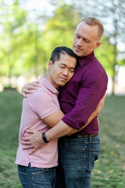rodzina homoseksualna para gejów przytulających się z zamkniętymi oczami stojących w parku na ulicy miejskiej