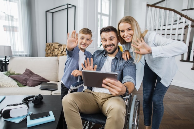 Zdjęcie rodzina i tata na wózku inwalidzkim pozuje przed kamerą w domu