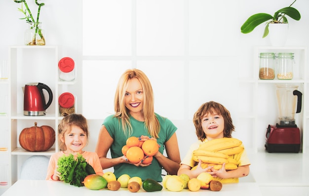 Rodzina matka i córka i syn mieszają smoothie ze zdrowymi składnikami owoców w kuchni