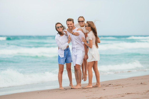 Rodzina młodego rodzica i dwójki dzieci uśmiecha się i cieszy razem na wakacjach na plaży