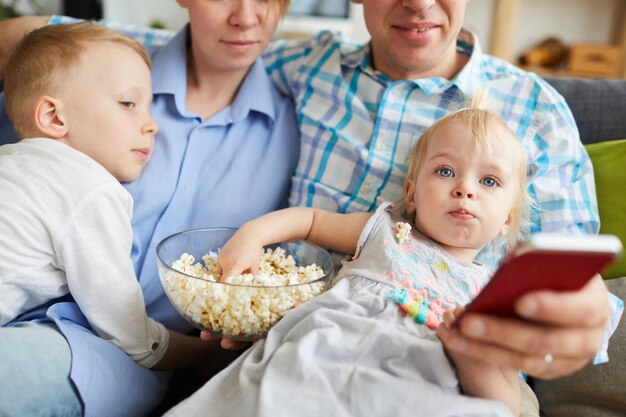 Rodzina ogląda telewizję i je popcorn