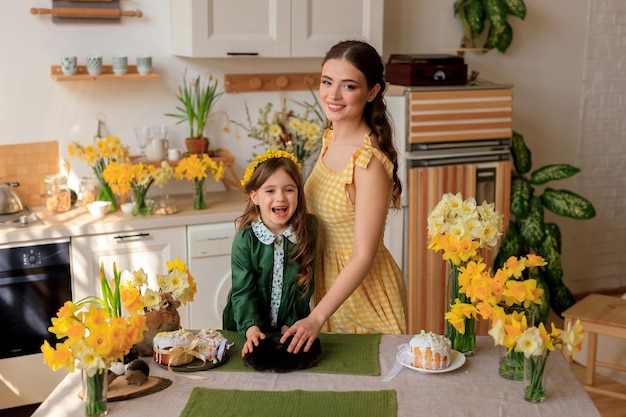 Rodzina świętuje Wielkanoc piękna dziewczyna i jej młoda mama w domu w kuchni przy świątecznym stole trzymają w rękach uroczego królika
