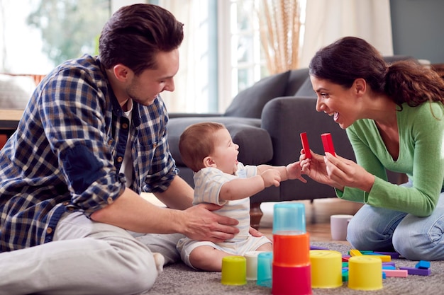 Rodzina transpłciowa z dzieckiem grająca w kolorowe zabawki w salonie w domu