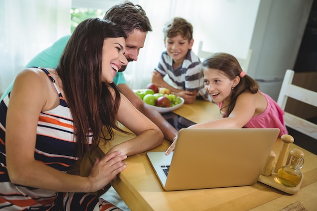 Rodzina używa laptop przy łomotanie stołem
