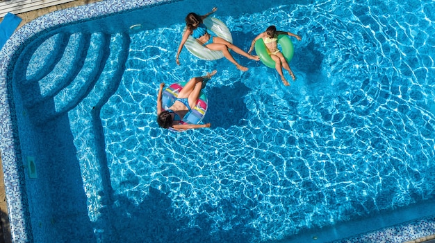 Rodzina w basenie widok z drona z lotu ptaka, szczęśliwa matka i dzieci pływają na nadmuchiwanych pierścieniowych pączkach i bawią się w wodzie na wakacjach rodzinnych, tropikalne wakacje w ośrodku