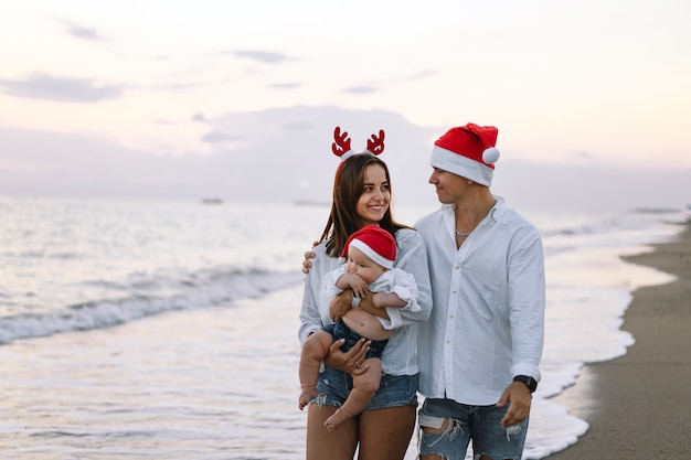 Rodzina W Czerwonej Czapce Mikołaja Spaceruje Po Plaży Rodzina świętuje Boże Narodzenie I Nowy Rok W Tropikach