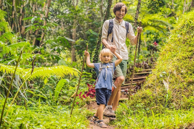 Rodzina w turystyce. Tata i syn spacerują po lesie z kijkami trekkingowymi