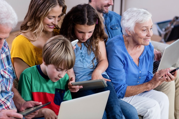 Zdjęcie rodzina wielopokoleniowa korzystająca z laptopa, tabletu i telefonu