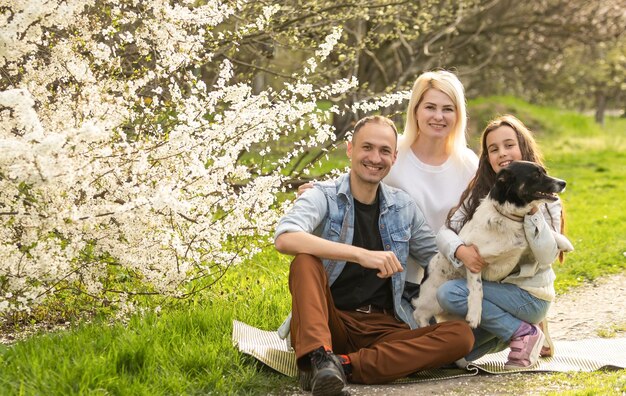 Rodzina z córką i psem bawią się razem w ogrodzie wiosną