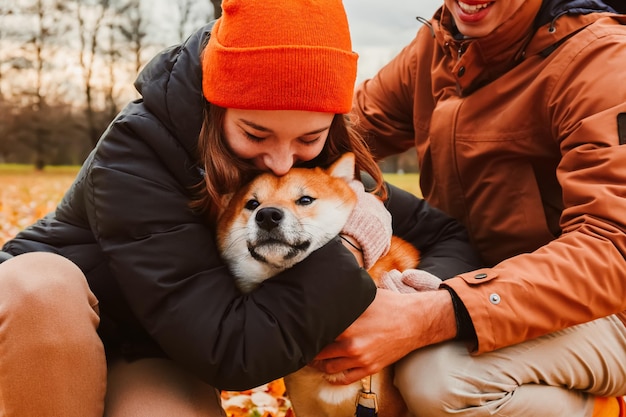 Rodzina z miłością przytula psa Uśmiechnięty szczęśliwy pies Właściciele spacerują z psem w parku i głaszczą go Rasa Akita Inu Zdrowie psychiczne i stres przez zwierzaka Ludzie przytulają psa