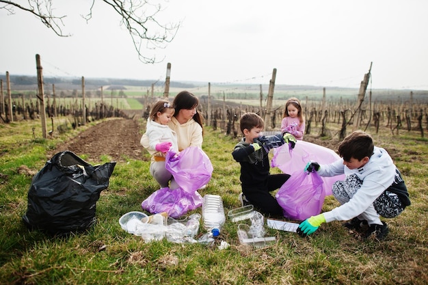 Zdjęcie rodzina z workiem na śmieci zbierająca śmieci podczas sprzątania w winnicach ochrona środowiska i recykling ekologiczny