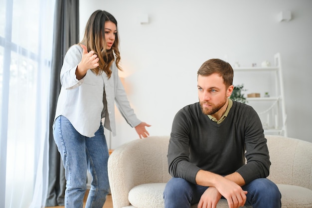 Rodzinna kłótnia mężczyzna i kobieta siedzący na kanapie w domu wściekła kobieta krzyczy na męża