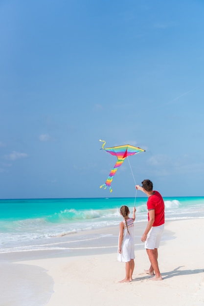 Rodzinna latająca latawiec razem na tropikalnej plaży biały