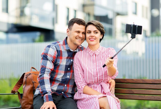 Zdjęcie rodzinna para z wózkiem dziecięcym robiąca selfie w mieście