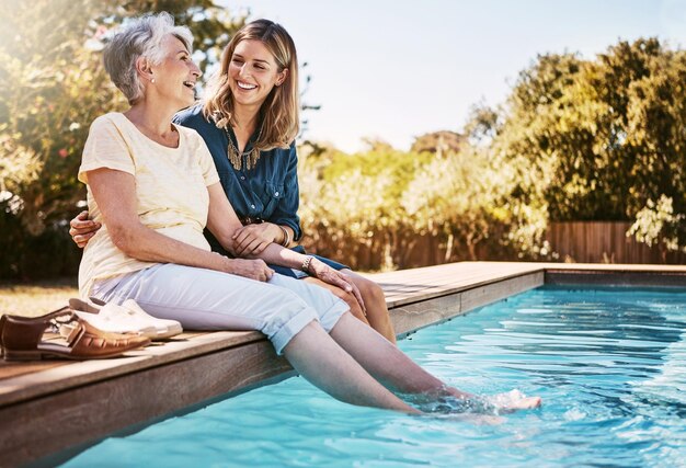 Rodzinne kobiety przy basenie i relaks razem z miłością i troską o jakość czasu na letnich wakacjach Starsza matka córka i wakacyjny odkryty basen i styl życia wellness ze szczęśliwą rodziną