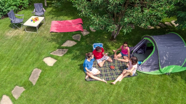 Rodzinne wakacje na campingu z lotu ptaka z góry, rodzice i dzieci odpoczywają i bawią się w parku, namiocie i sprzęcie kempingowym pod drzewem, rodzina w obozie na świeżym powietrzu koncepcja