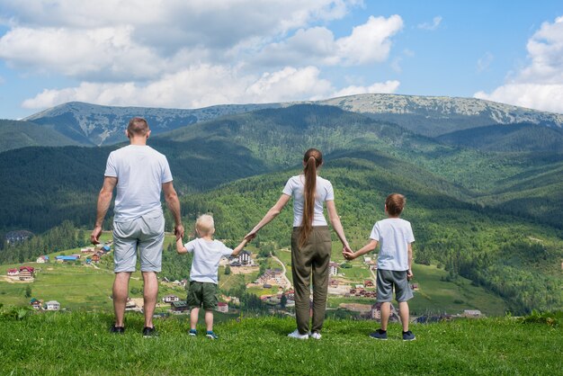 Rodzinne Wakacje. Rodzice I Dwaj Synowie Podziwiają Widoki Na Dolinę. Góry W Oddali. Widok Z Tyłu