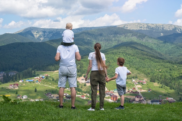 Rodzinne Wakacje. Rodzice I Dwaj Synowie Podziwiają Widoki Na Dolinę. Góry W Oddali. Widok Z Tyłu