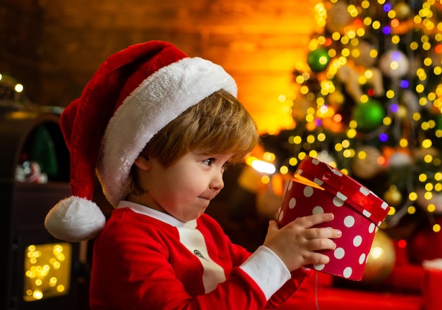 Rodzinne wakacje. Wspomnienia z dzieciństwa. Święty chłopiec świętują Boże Narodzenie w domu. Chłopiec dziecko grać ozdób choinkowych. Wesołych i jasnych świąt. Aktywność i gra w dzieciństwie. Świąteczne atrybuty