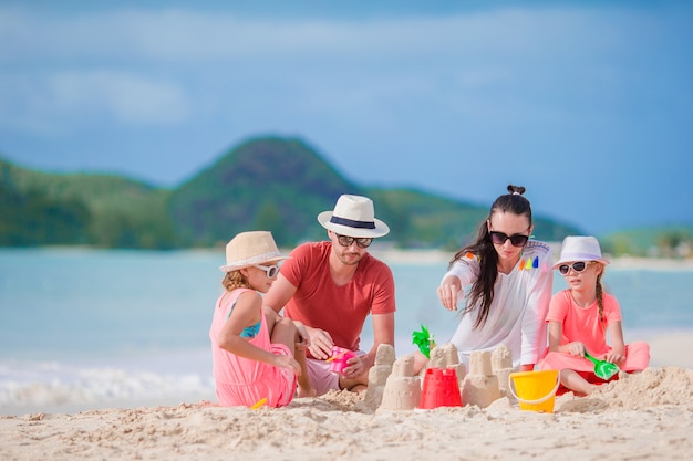 Rodzinny robi piaska kasztel na biel plaży na wakacjach letnich