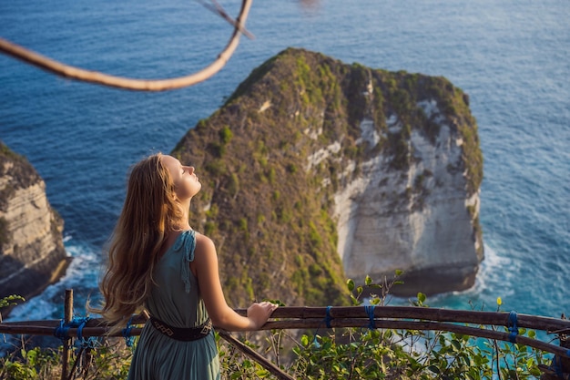 Rodzinny styl życia na wakacje Szczęśliwa kobieta stoi w punkcie widokowym Spójrz na piękną plażę pod wysokim klifem Cel podróży na Bali Popularne miejsce do odwiedzenia na wyspie Nusa Penida