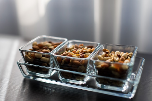 Zdjęcie rodzynki, orzeszki ziemne i pistacje w eleganckich szklanych miseczkach