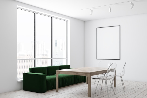 Róg białej jadalni z drewnianą podłogą, drewniany stół z przezroczystymi krzesłami i zieloną kanapą w pobliżu i pionowym plakatem na ścianie.