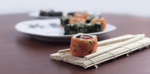 Roladki sushi i pałeczki na drewnianym stole