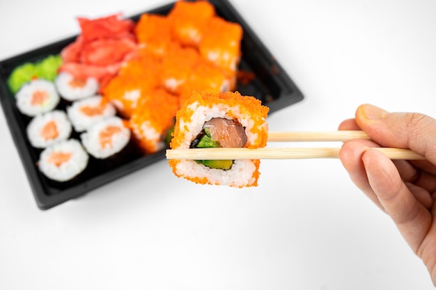 Roladki sushi na wynos w plastikowym pojemniku, kalifornia, rolka łosoś maki, różowy imbir, wasabi. koncepcja dostawy sushi