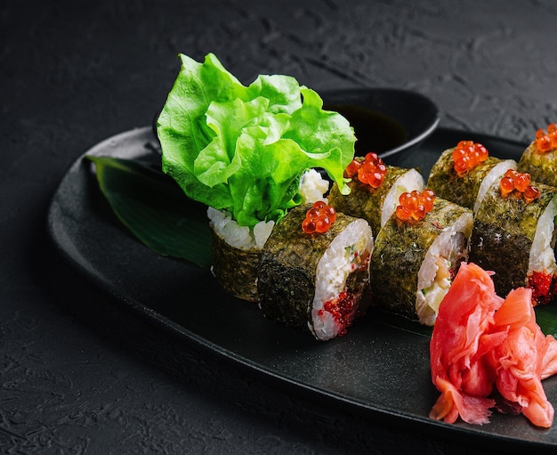 Roladki sushi podawane na czerwonym kawiorze z łupka kamiennego