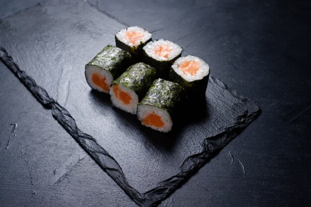 Roladki sushi z łososiem w nori na ciemnym tle. Kuchnia azjatycka i koncepcja kuchni japońskiej