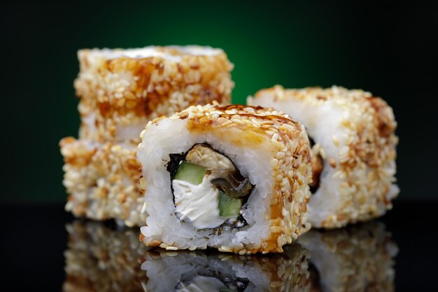 Roladki Unagi Maki Z Ogórkiem Sezamowym I Czerwoną Rybą Na Czarnym Tle