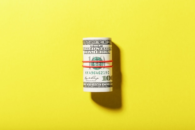 Rolka amerykańskich rachunków za sto dolarów jest wiązana z czerwoną gumką na żółtym tle.