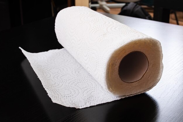 Rolka ręczników papierowych leży na drewnianym stole