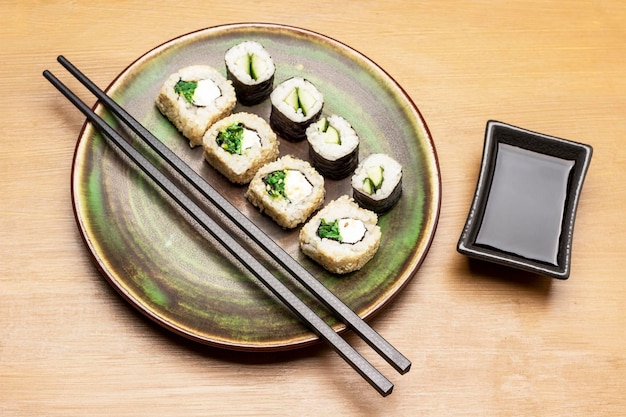 Rolki sushi i pałeczki na zielonym talerzu
