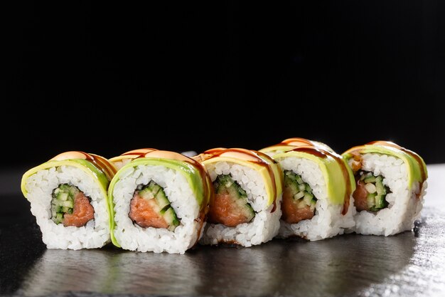 Roll sushi z zielonego smoka z łososiem, ogórkiem i awokado.