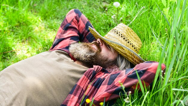 Rolnictwo i rolnictwo zrelaksowany rolnik w słomkowym kapeluszu dojrzały mężczyzna ogrodnik zrelaksuj się na zielonej trawie ciesz się wiosną przyrodą sezon letni w idealnym brutalnym ranczo hipster noś kraciastą koszulę zachowaj spokój