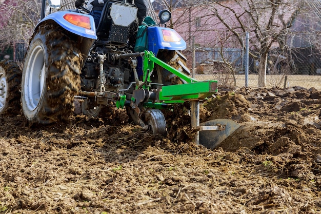 Rolnik orze pole. Mały traktor z pługiem w polu. Uprawa.