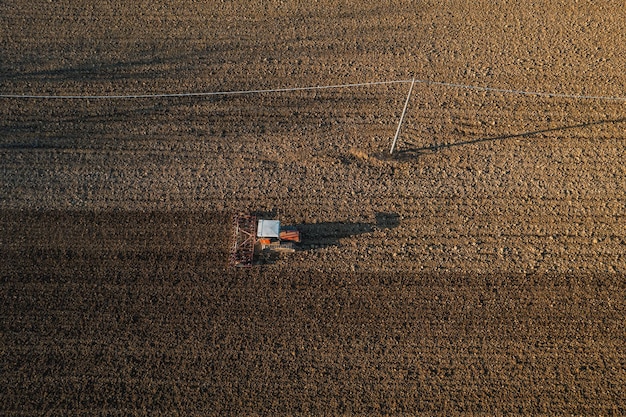 Rolnik prowadzący traktor gąsienicowy orający i bronujący kruszenie skorupy powierzchniowej w celu ułatwienia narodzin i wysiewu roślin na suchej glebie