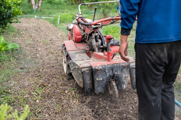 Rolnik prowadzący traktor odgarniający glebę na plantacji